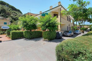 A two-story building with a paved driveway, surrounded by greenery and parked cars. - Apartment 'Stella Di Mare Beach' with Sea View, Private Terrace and Air Conditioning (Naregno)