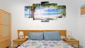 Ein Schlafzimmer mit einem Bett, zwei Nachttischen, einem Holzschrank und einer Wand mit drei gerahmten Bildern.