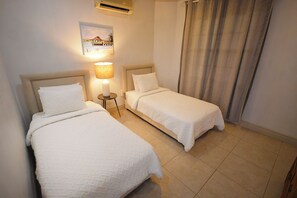 Ein Hotelzimmer mit zwei Betten, einer Lampe, einem Bild an der Wand und einem Vorhang.