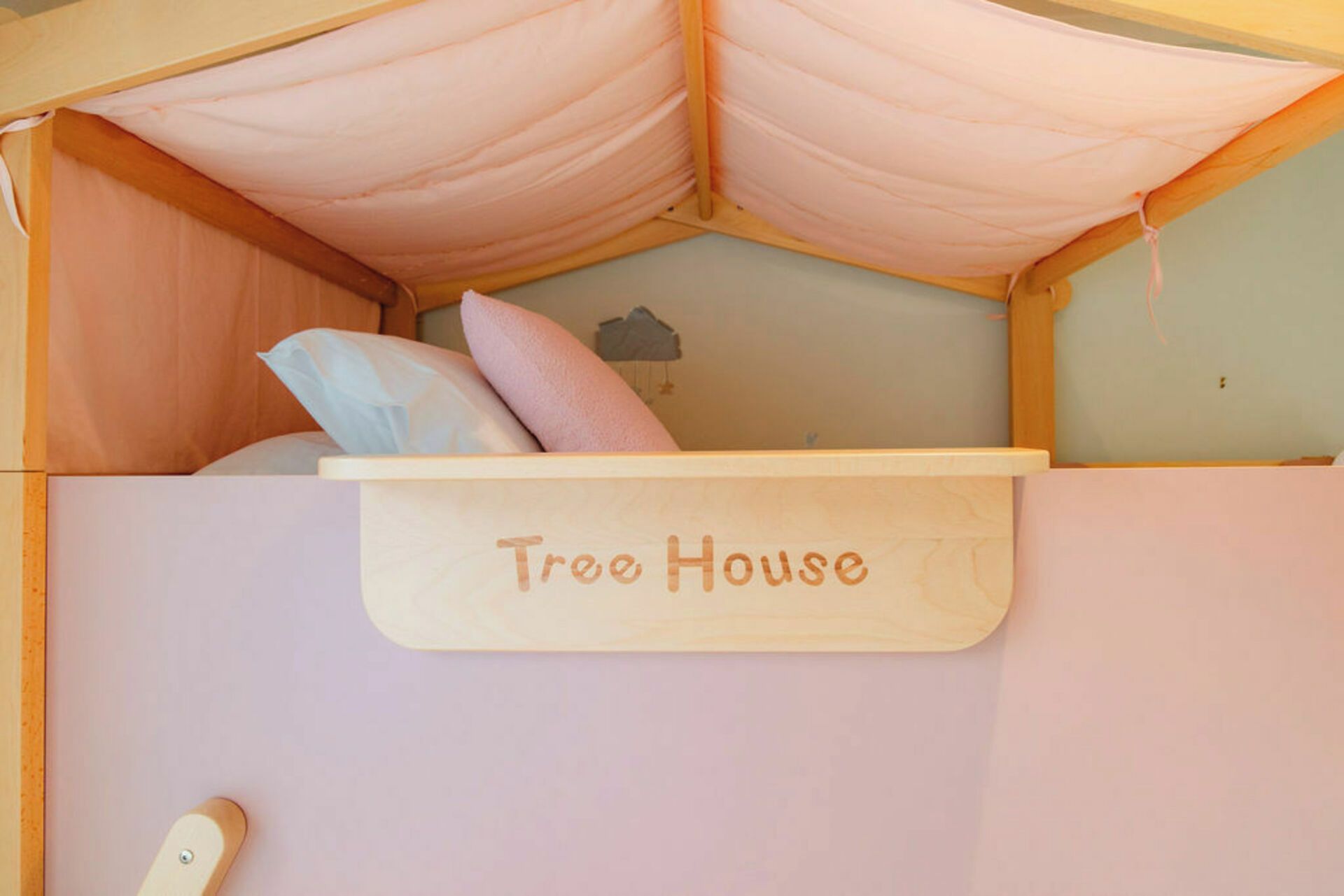 A children's bunk bed with a canopy labeled 'Tree House' and pillows.