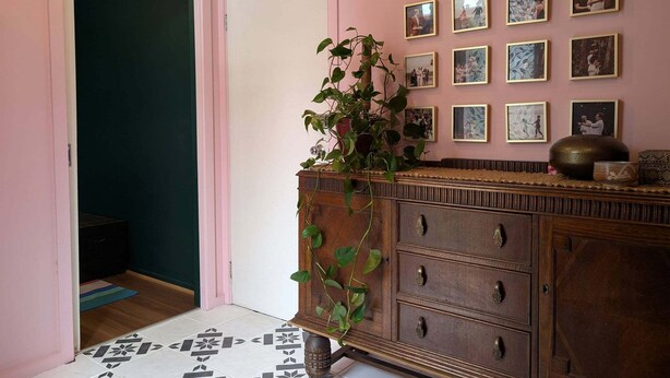 A hallway with a wooden dresser, a potted plant, and a wall of framed photographs. - Stylish and Comfortable Home in Preston (Preston)