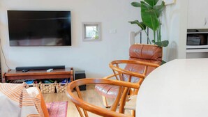 A living room with a flat-screen TV, a wooden chair, a small table, and a plant. - Stylish and Comfortable Home in Preston (Preston)