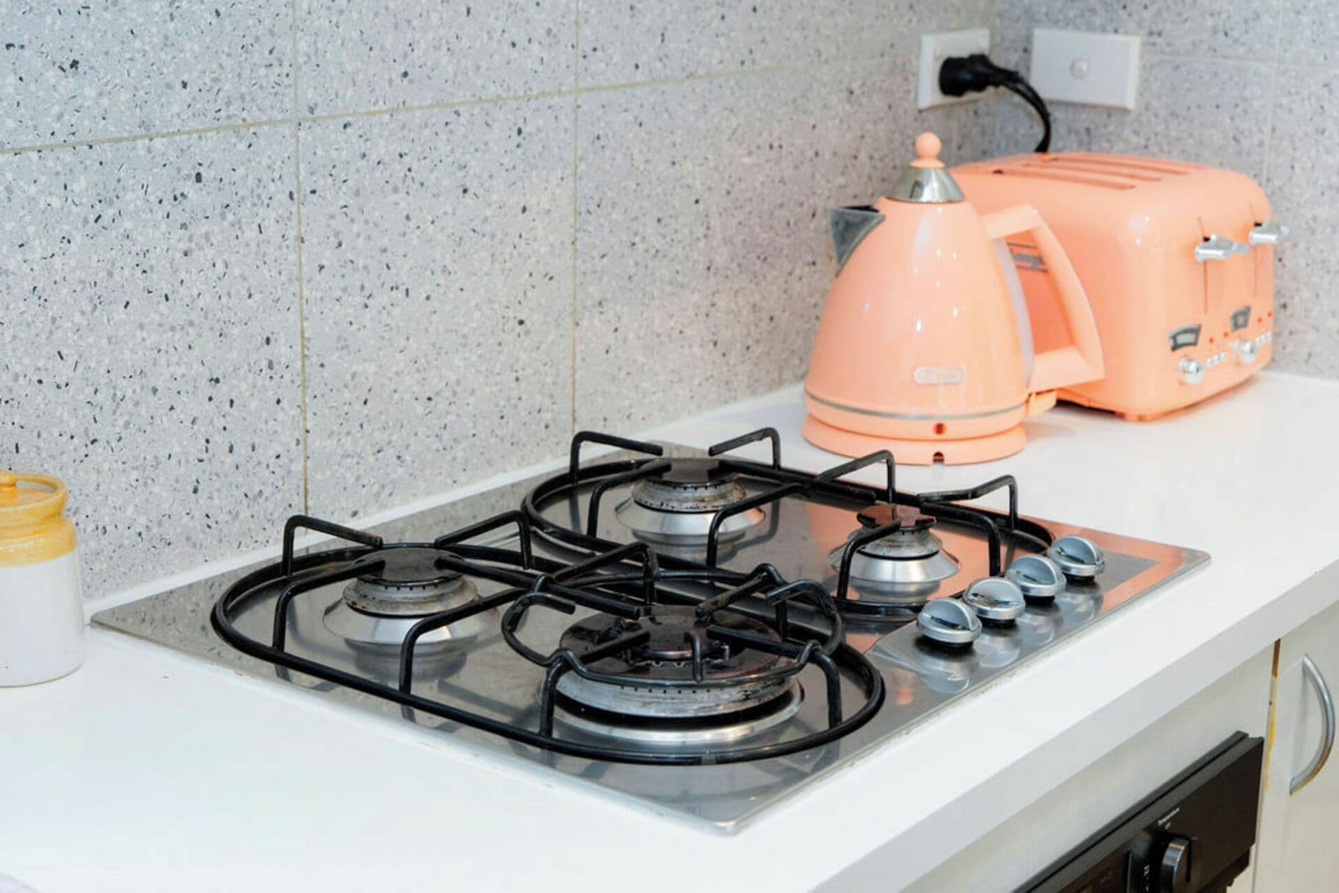 A kitchen with a gas stove, a toaster, and a kettle on a countertop.