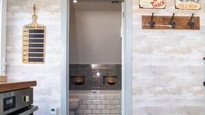 Ett kök med en träpanel bakom diskbänken, en diskho och en bänkskiva. På väggen finns en anslagstavla för köksrelaterade lappar och en skylt för en liten restaurang som serverar krabba.