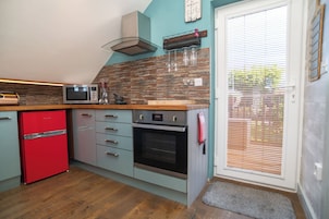 Una cocina con microondas, horno y refrigerador rojo.