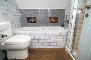 A bathroom with a toilet, a bathtub, and two wall-mounted sinks with built-in lighting. - Garden View Apartment (Kingsbridge)