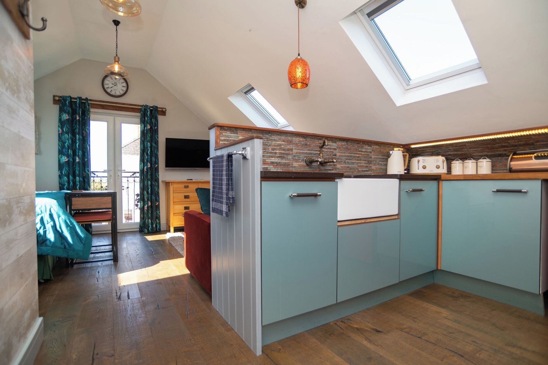 A kitchen with a skylight, wooden cabinets, a refrigerator, and a dining area with a table and chairs.