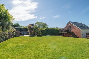 A house with a fenced yard, a patio with outdoor furniture, and a covered area. - Garden View Apartment (Kingsbridge)