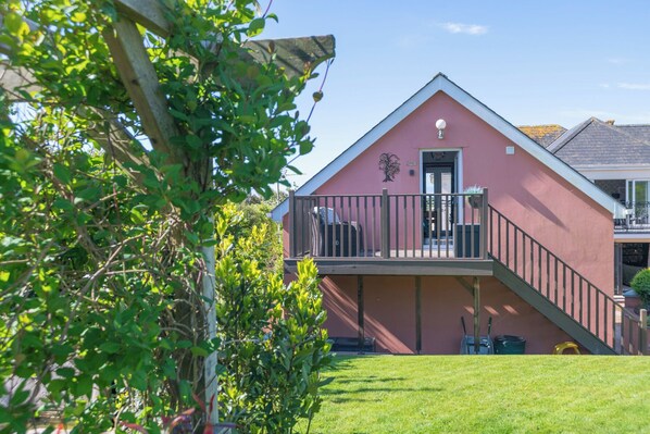 A pink building with a balcony, a door, and a small garden area. - Garden View Apartment (Kingsbridge)