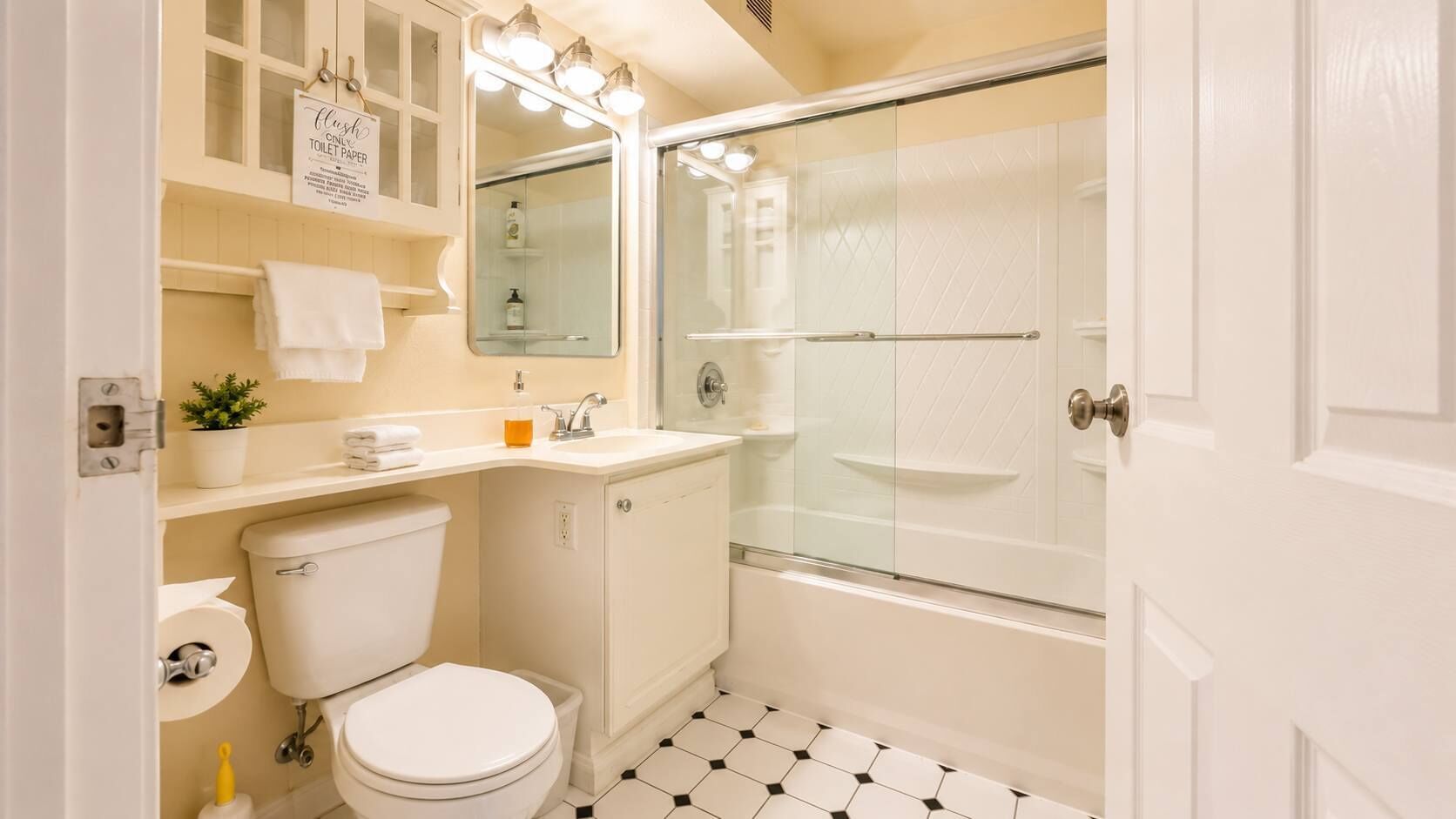 Een badkamer met toilet, wastafel, spiegel en douche.