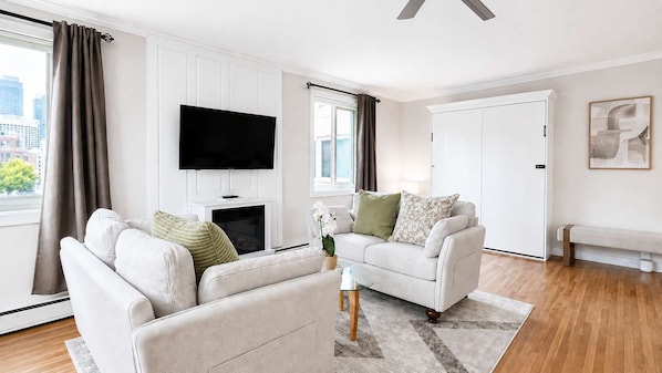 Ein Wohnzimmer mit Flachbildfernseher, zwei Sofas, einem Couchtisch, einem Kamin und einer Bank.