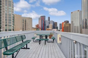 Eine Dachterrasse mit Blick auf eine Stadtlandschaft, inklusive Tisch und Bänken.