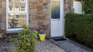 A stone building with a white door marked '39' and a window with a view of a street. - Tin Lantern Cottage (Redruth)