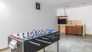 A room with a foosball table, a television, and a wooden cabinet. - Son Barba Mallorca – Luxury, Privacy, Private Pool & Jacuzzi, AC, BBQ, More (Sa Pobla)