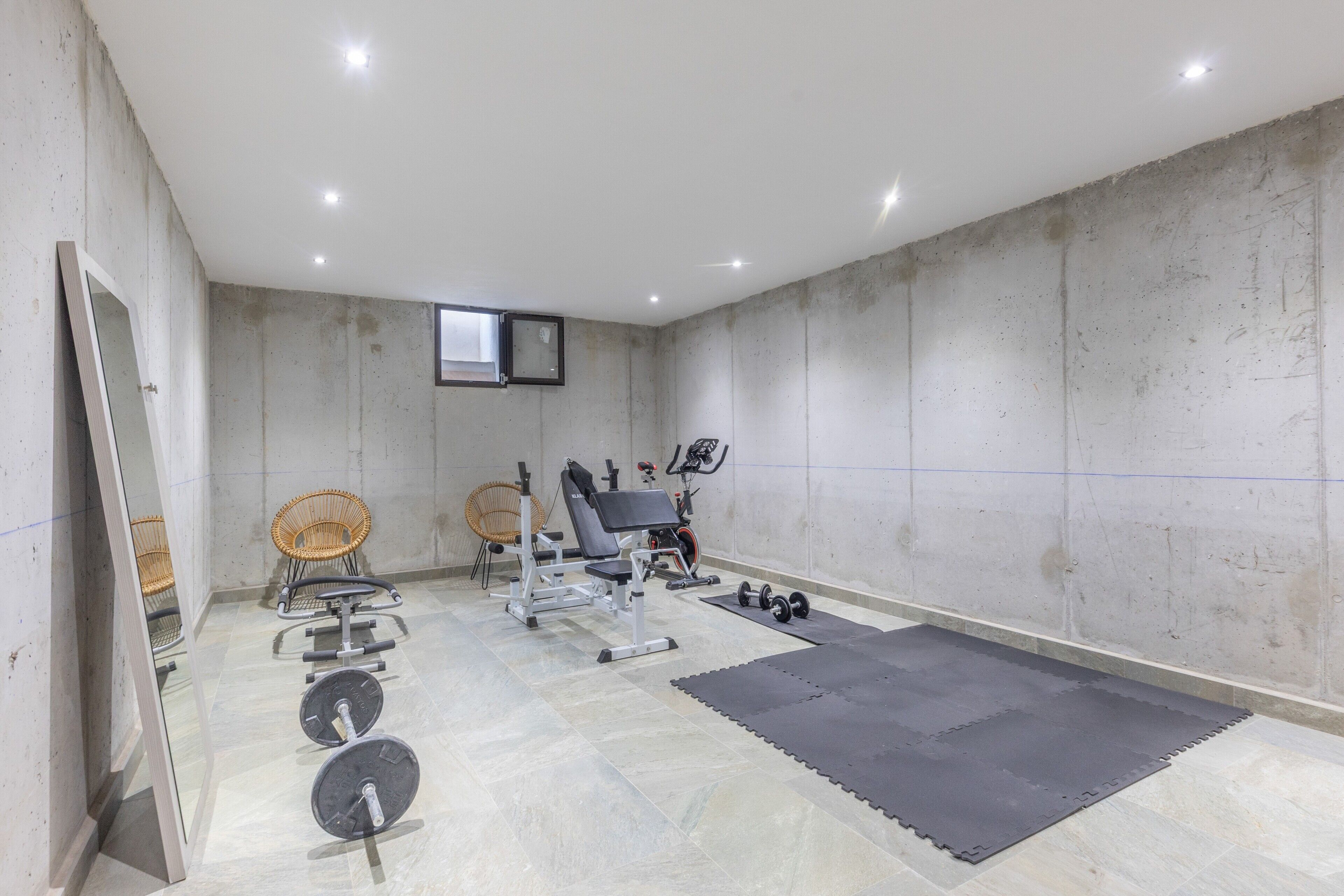 Ett gym med träningsutrustning, en TV som hänger på väggen och ett fönster.