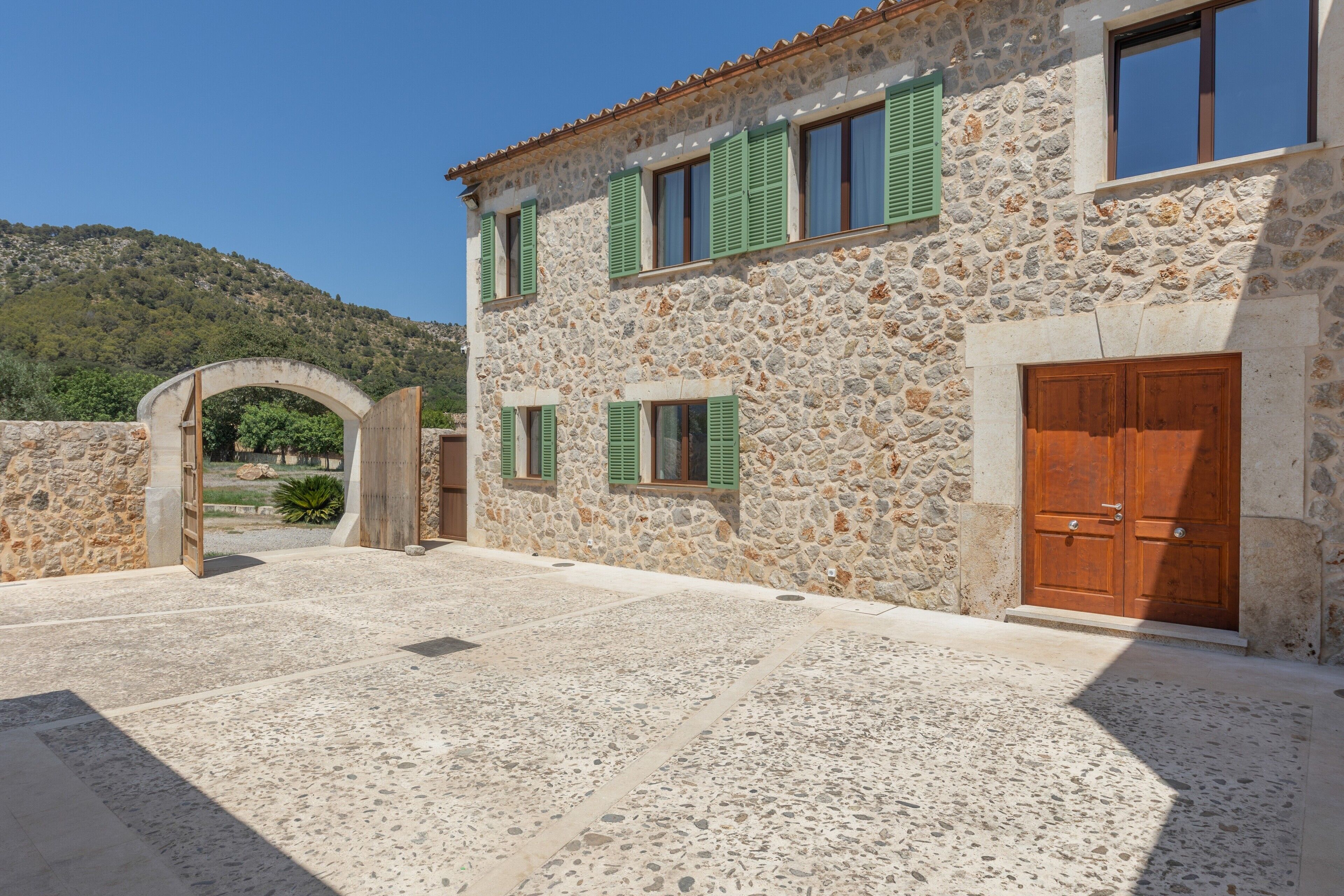A stone building with a courtyard, a wooden door, and a stone archway.