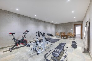 Un gimnasio con equipo de ejercicio, una banca y un televisor instalado en la pared.