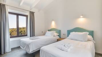 Habitación de hotel con dos camas, un ventanal grande y vistas a árboles.