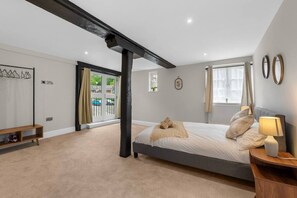 A bedroom with a bed, bedside table, lamp, and a view of the outside.