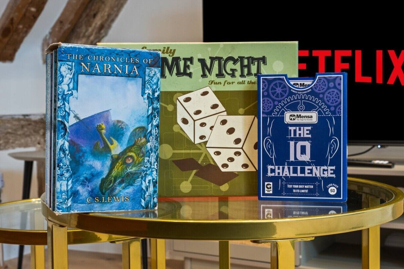 Tres libros sobre una mesa de vidrio con un televisor al fondo.