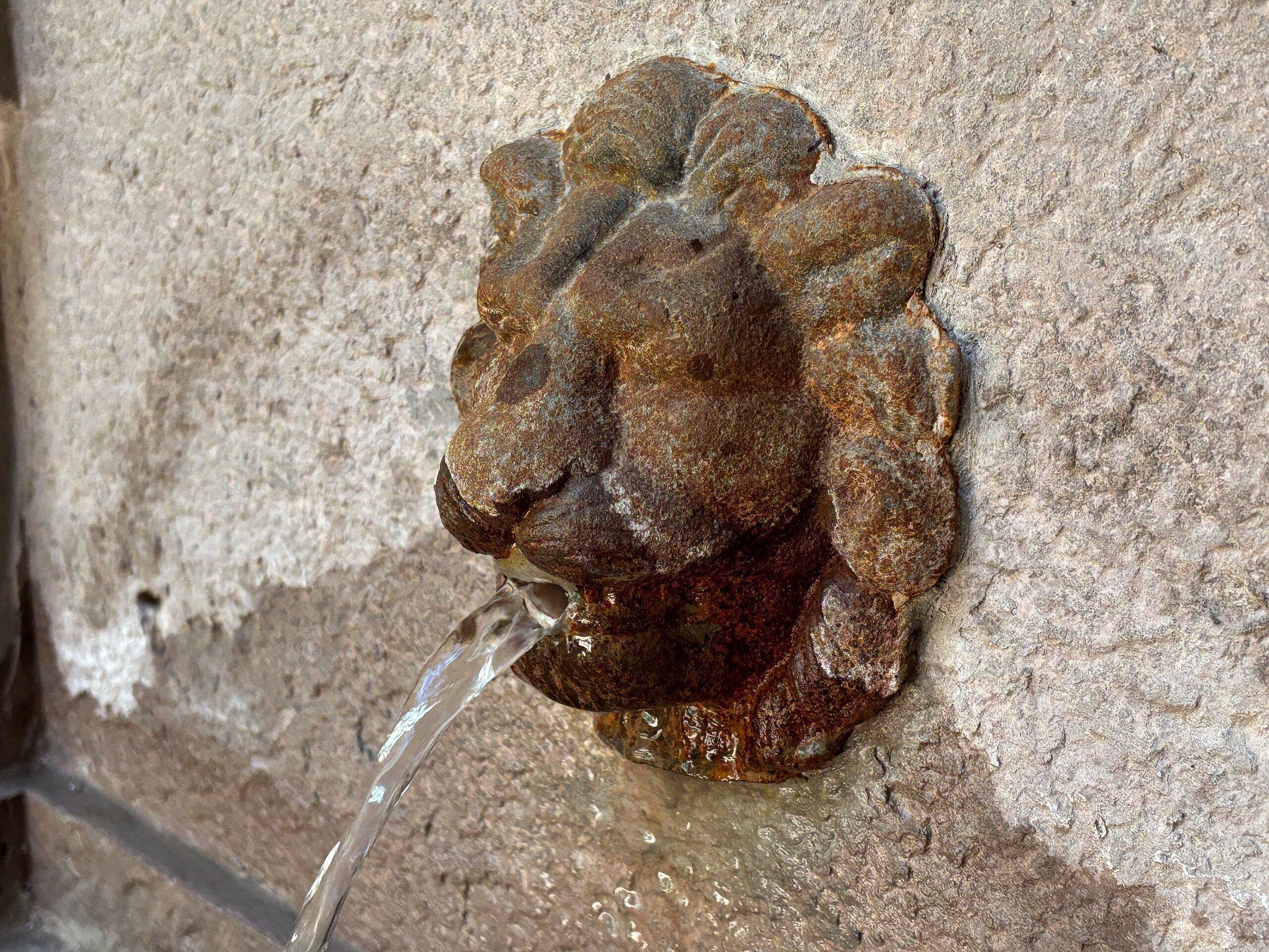 A stone wall with a water spout.