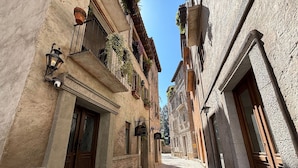 Una estrecha calle adoquinada bordeada por edificios históricos con balcones, puertas de madera y barandillas de hierro forjado.