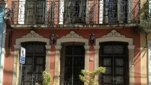 A building with ornate iron gates, a balcony with a wrought iron railing, and two potted plants in front. - Direita S.Antonio-Plus Quarto e sala para 5 pessoas, vista baia Todos os Santos (Salvador)