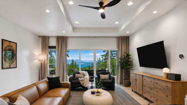 A modern living room with a sofa, chairs, a coffee table, a TV, and a balcony with a view. - Group Retreat Near Glacier | Lake Views (Somers)
