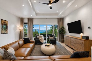 Un salon moderne comprenant un canapé, des fauteuils, une table basse, un téléviseur et un balcon avec vue.