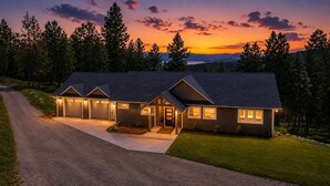 A modern two-story house with a driveway, garage, and a well-maintained lawn. - Group Retreat Near Glacier | Lake Views (Somers)