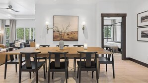 A modern dining area with a wooden table, black chairs, and a vase with branches. - Group Retreat Near Glacier | Lake Views (Somers)