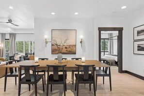A modern dining area with a wooden table, black chairs, and a vase with branches. - Group Retreat Near Glacier | Lake Views (Somers)