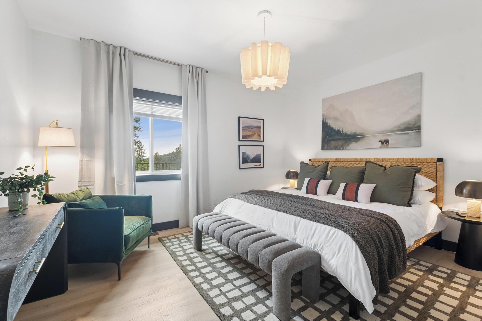 Een slaapkamer met een bed, een bankje, bureau, stoel en kunst aan de muur.