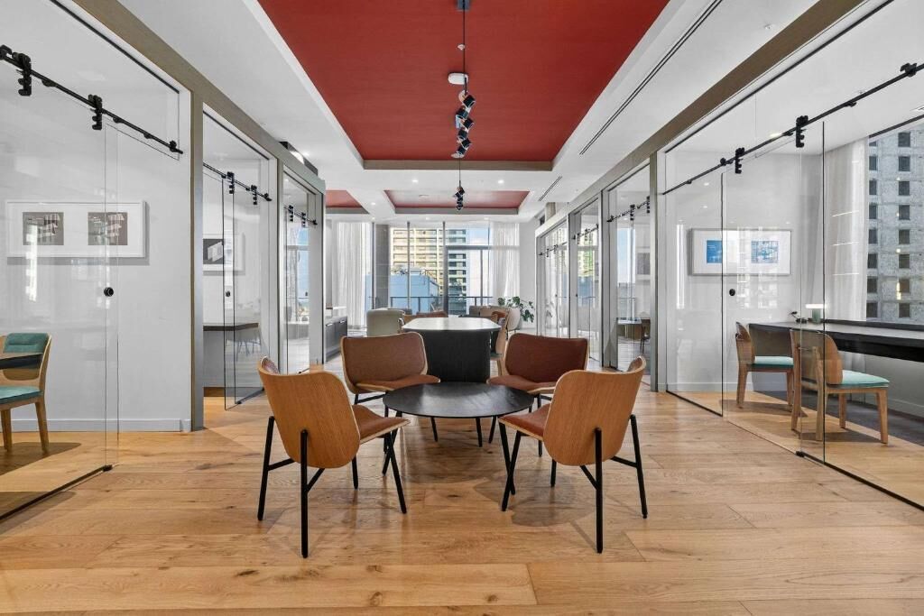 Un intérieur moderne avec des murs en verre, une table ronde entourée de chaises et un plafond rouge.