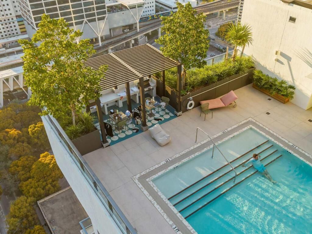 An outdoor swimming pool with a pergola, lounge chairs, and a small bar area.