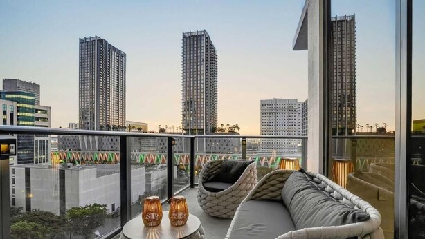 A balcony with a sofa, two round tables, and two vases. - The Crosby Miami Worldcenter (Miami)