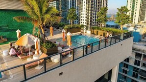 A rooftop pool area with lounge chairs, umbrellas, and a view of the cityscape. - The Crosby Miami Worldcenter (Miami)