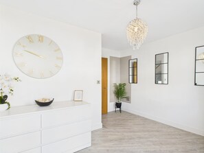 A modern interior with a white wall clock, a chandelier, and a minimalist design. - Modern Home • Walk to Town • Garden w/ Log Fire (Royal Tunbridge Wells)