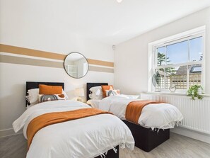 A hotel room with two beds, a large window, a mirror, and a radiator. - Modern Home • Walk to Town • Garden w/ Log Fire (Royal Tunbridge Wells)
