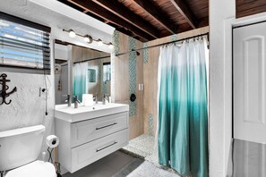 A bathroom with a white vanity, a mirror, a shower curtain, and a window with blinds. - La Pirata: Hgtv-Remodeled 3BR/2BA Canal Home w/ Pool (Marathon)