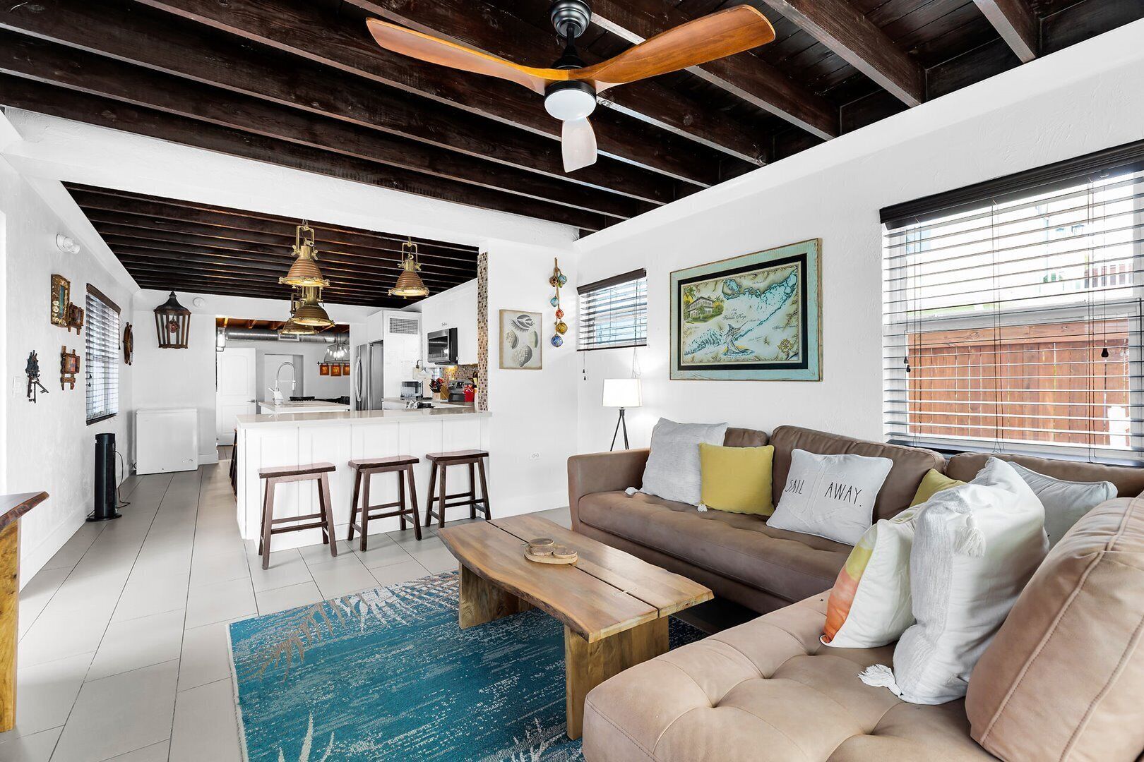 A modern living room with a sofa, coffee table, and a dining area with stools.