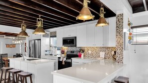 A modern kitchen with white cabinetry, a large island, bar stools, and pendant lighting. - La Pirata: Hgtv-Remodeled 3BR/2BA Canal Home w/ Pool (Marathon)