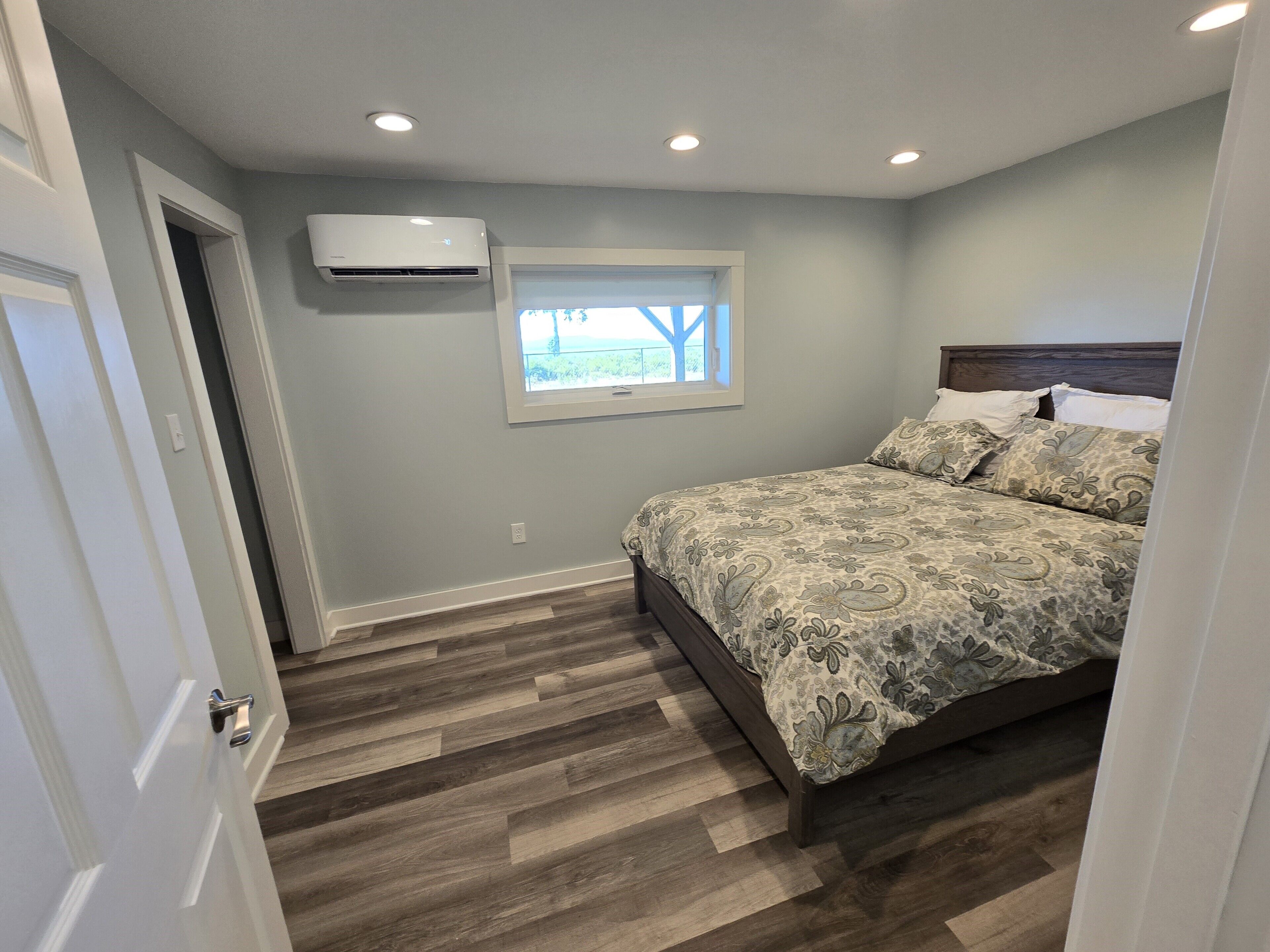 Une chambre à coucher avec un lit, une fenêtre et un appareil de climatisation.