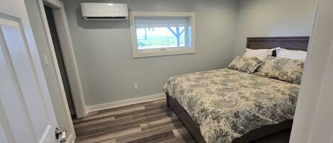 A bedroom with a bed, a window, and an air conditioning unit.