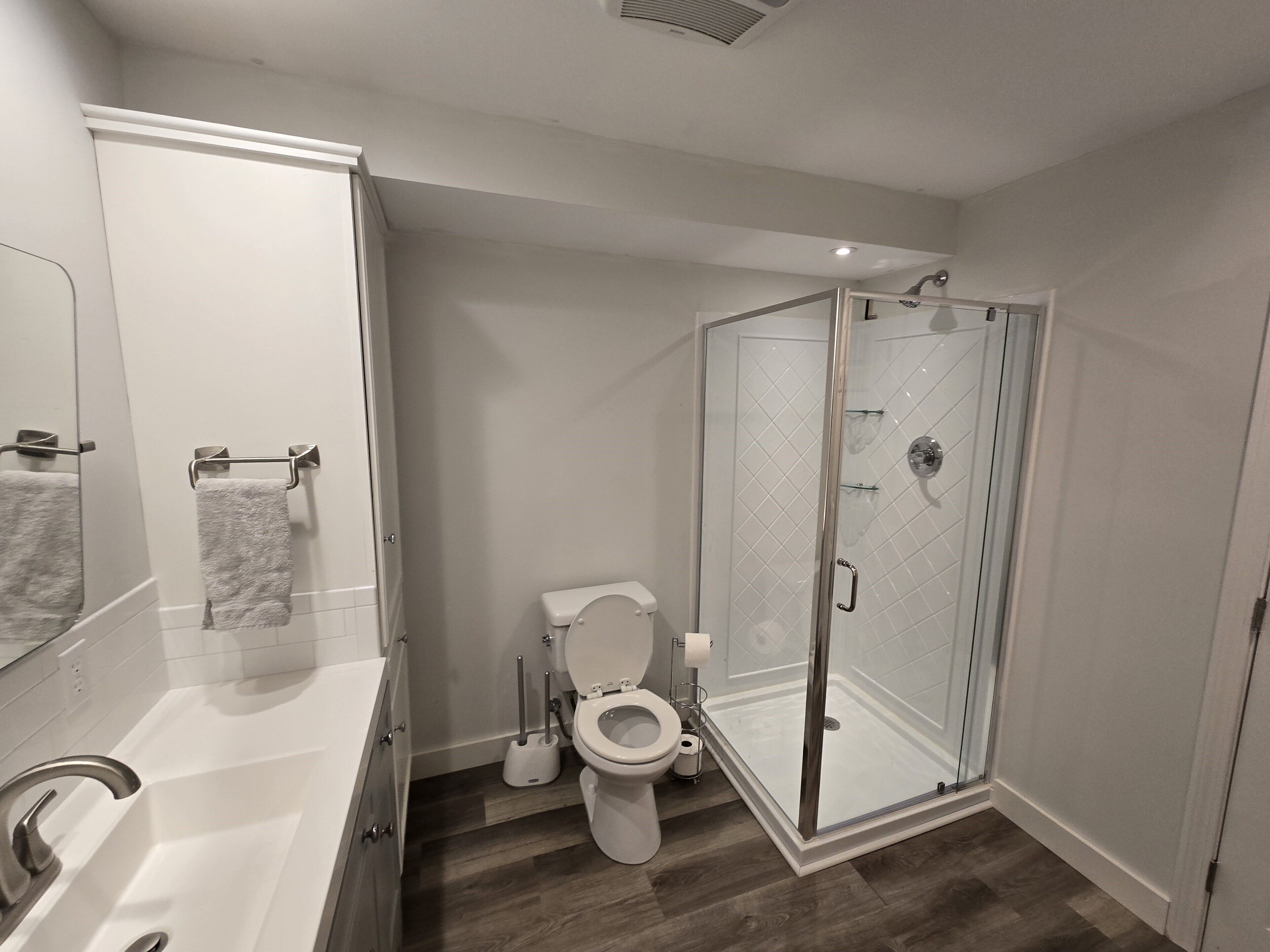A modern bathroom with a shower, toilet, and sink.