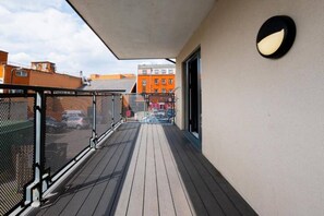 Ein Balkon mit einem Maschendrahtzaun, Blick auf Gebäude und eine Tür.