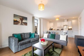 Ein modernes Wohnzimmer mit einem grauen Sofa, einem Couchtisch und einem Gemälde an der Wand.
