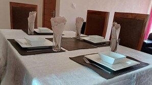 Taula de menjador preparada amb plats, bols i draps de paper blancs, i caires al voltant.