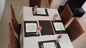 Taula de dinar coberta amb plats blancs, sotsplats negres i gots de vidre transparent.