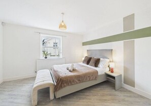 A bedroom with a bed, bedside table, lamp, window, and a view of the outside. - Pristine Home • Near Station, Pantiles & Calverley (Royal Tunbridge Wells)